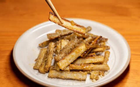 Delicious crispy fried burdock root served on a white plate with chopsticks.