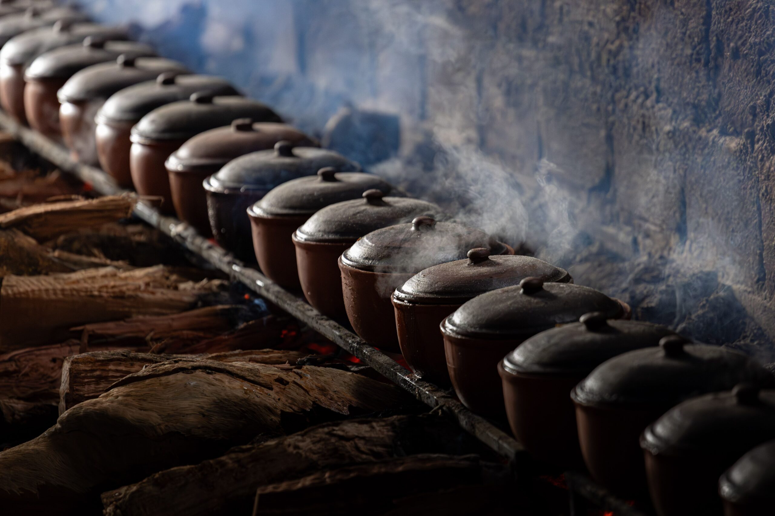 Row of steaming clay pots over firewood, showcasing authentic Vietnamese cooking.