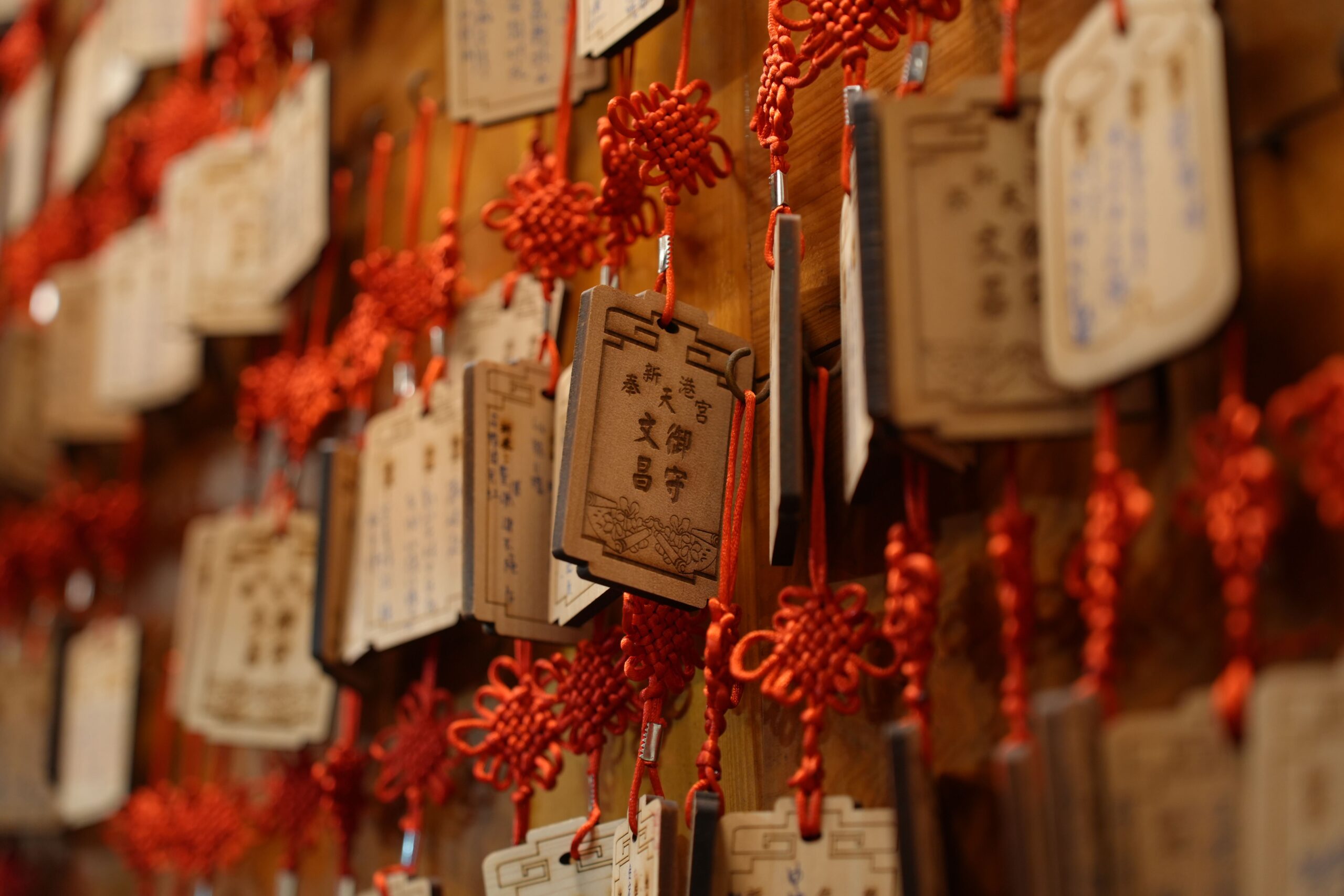 Hanging wooden prayer plaques with red knots in Chiayi County, Taiwan, symbolizing cultural heritage.